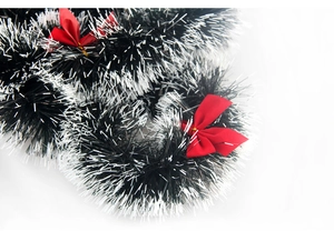 Close-up of dark green and white Christmas tinsel garland with red silk bows decor