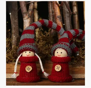 Close-up of red and grey knitted Christmas gnomes with striped hats on a rustic background