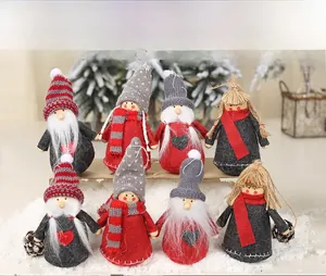 Close-up of handmade Nordic Christmas gnomes with knit hats and plush beards on snow