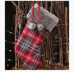 Detail of plaid Christmas stocking with grey faux fur cuff and hanging pompom ornaments