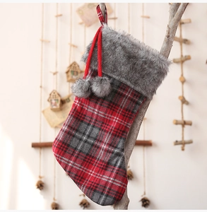 Detail of red and grey plaid Christmas stocking with soft faux fur trim and pom-poms