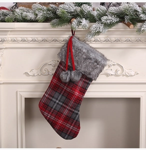 Classic plaid Christmas stocking with gray faux fur trim hanging on a festive fireplace