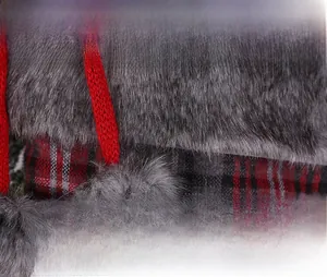 Detail of red and black plaid Christmas stocking with grey faux fur trim and pom-poms