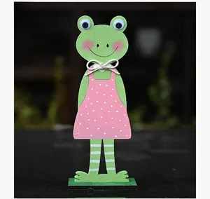 Detail van een handgemaakt houten kikkerfiguur met een polka dot jurk en een jute strik