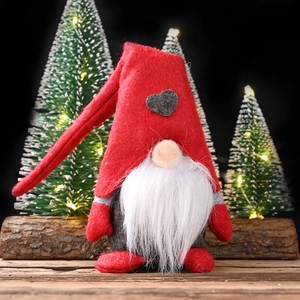 Plush Christmas gnome with red heart hat and white beard on rustic wooden stand