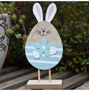 Detail view of a handcrafted wooden Easter bunny ornament with blue stripes in a garden