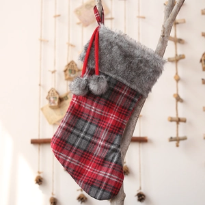 Plaid Christmas stocking with grey faux fur cuff and pom poms hanging on branch