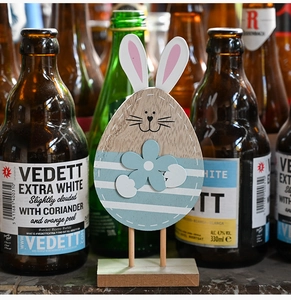 Close-up of a rustic wooden Easter bunny ornament with blue stripes on a wooden base