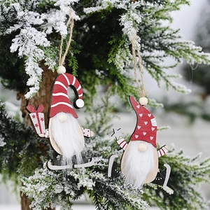 Close-up of wooden Christmas gnomes hanging on snow-covered pine branches in winter