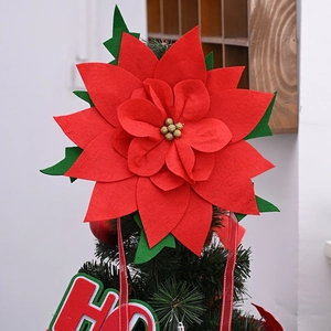 Macro detail of red felt poinsettia Christmas tree topper with gold glitter and HO HO HO ribbon