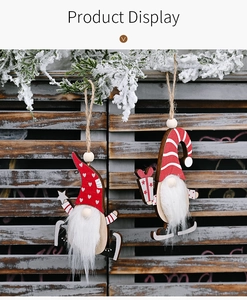 Detail of wooden Christmas gnomes with plush beards hanging on snow-covered pine branches
