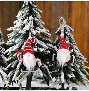 Detail of wooden Christmas gnomes ornaments with faux fur beards hanging on snowy tree