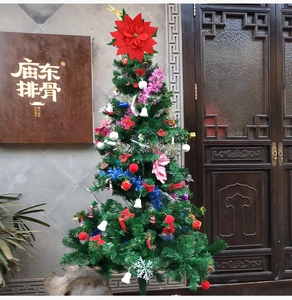 Detailed view of artificial Christmas tree decorated with red poinsettia and ornaments