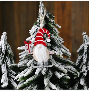 Close-up of wooden Christmas gnome ornament with white beard on a snowy pine branch