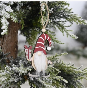 Close-up of wooden Christmas gnome ornament with red hat and skates hanging on a snowy tree