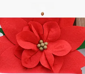Close-up of red felt Christmas flower with golden glitter center and green leaves