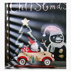 Macro detail of wooden Santa Claus driving a car with a mini flocked pine tree decoration