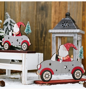 Close-up of wooden Santa Claus in grey car with mini pine tree on snowy background