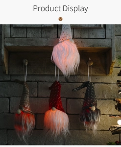 Détail de quatre gnomes de Noël lumineux avec chapeaux à paillettes sur mur brique