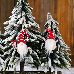 Wooden Christmas gnome hanging ornaments with red hats on snowy pine tree branches