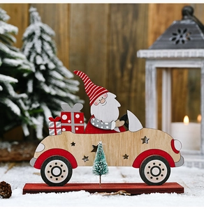 Close-up of wooden Santa driving a car with a Christmas tree and gifts on a red base