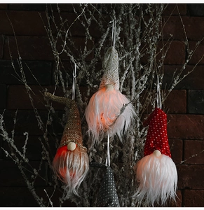 Détail de gnomes de Noël lumineux avec LED suspendus devant un mur de briques
