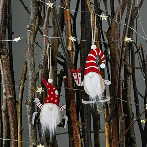 Wooden Christmas gnome ornaments with hats and gifts hanging on lit branches