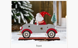 Front view of wooden Santa driving a grey car with a mini pine tree on a red base