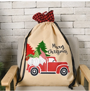 Linen Christmas gift bag with gnomes and red truck print on a grey armchair