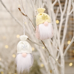 Close-up of two knit gnomes with sequin snowflakes on warm bokeh light background