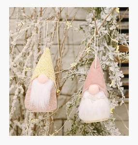 Detail of Christmas gnome ornaments with knit hats and wooden bases on snowy branches