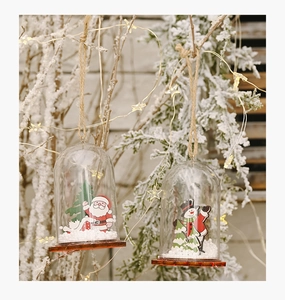 Detail of Christmas ornament with Santa inside transparent dome on snowy pine branch