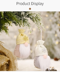 Close-up of plush Christmas gnome ornaments with sequined hats hanging on snowy pine branches
