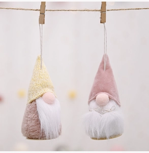 Detail of two plush Christmas gnomes hanging on a rope with cozy knit and velvet hats