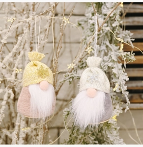 Detail of Christmas gnome ornaments with knit hats and plush beards on snowy branches