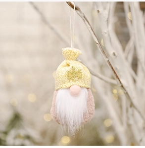 Macro detail of a plush Christmas gnome ornament hanging on a branch with festive lighting