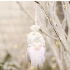 Detail of plush gnome Christmas ornament with sequin snowflake hat hanging on a tree