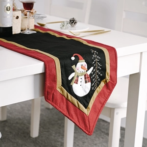 Detail of Christmas table runner featuring festive snowman embroidery and gold pine motifs