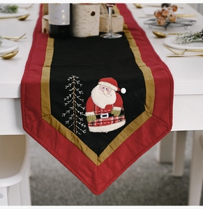 Detail of Christmas table runner featuring Santa Claus embroidery and satin edges
