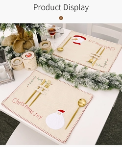 Détail d'un set de table de Noël en lin avec broderie Père Noël et rangement de couverts