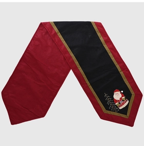 Close-up of Christmas table runner featuring red and black fabric with Santa Claus embroidery