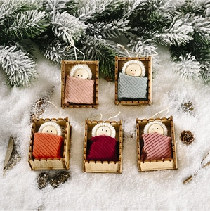 Detailed overhead shot of five knit baby dolls in wooden cradles for Christmas tree decor