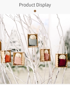 Detailed view of handmade fabric dolls in wooden boxes hanging on white branches