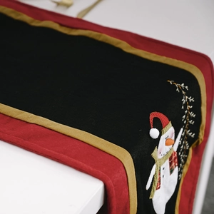 Christmas table runner with snowman embroidery in festive red, black, and gold colors