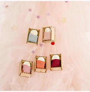 Close-up of five handmade wooden doll ornaments in knit blankets for Christmas