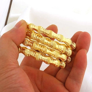 Set van vier gouden getextureerde armbanden met golfpatronen en gepolijste afwerking