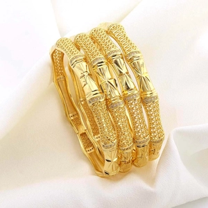 Set of four 18K gold plated bamboo bangles with sparkling crystals on white fabric
