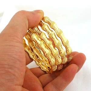 Detailopname van de vergulde armbandenset met golvend textuurontwerp en gespsluiting