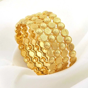 Set van vier 24k vergulde armbanden met honingraatmotief op witte stof