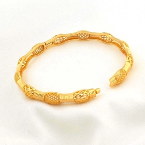 Dettaglio macro del bracciale dorato con fibbia a cuore traforata e trame a onda